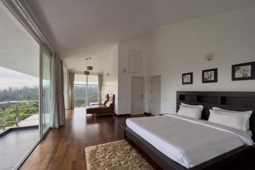 a bedroom with a large bed and a balcony at StayVista at The Lilly with Breakfast & Yoga in Ooty