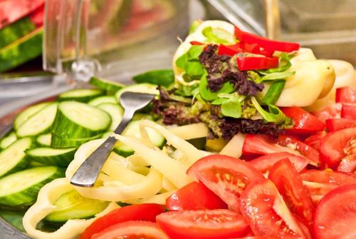 a plate of vegetables and a salad with a knife at Hotel Klastrom in Győr