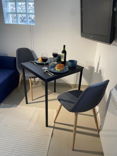 une table avec une assiette de nourriture et deux verres de vin dans l'établissement Studio D Cosy Parc des expositions Roissy CDG Airport, à Vaujours