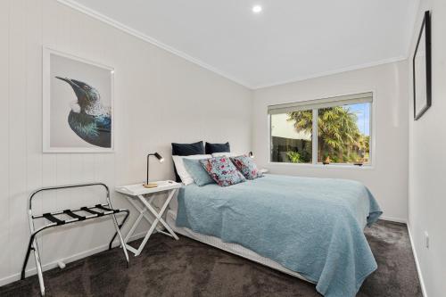 een slaapkamer met een bed, een stoel en een raam bij River Rest - Ruakaka Holiday Home in Ruakaka