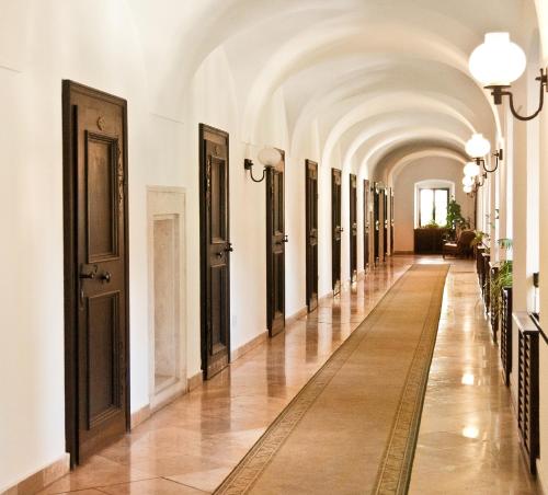 un couloir dans un bâtiment aux murs blancs et à une arcade dans l'établissement Hotel Klastrom, à Győr