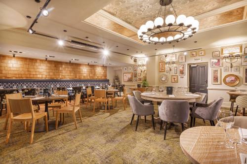 a restaurant with tables and chairs and a chandelier at The Wynnstay Hotel, Oswestry, Shropshire - The Coaching Inn Group in Oswestry