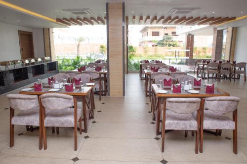 ein Restaurant mit Holztischen und -stühlen und einem großen Fenster in der Unterkunft Asian Buddha Hotel in Siddharthanagar