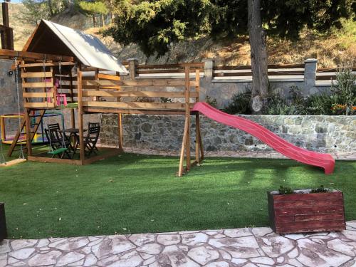 a playground with a red slide in a yard at DIAMOND Stone Wooden Guest House in Khandria