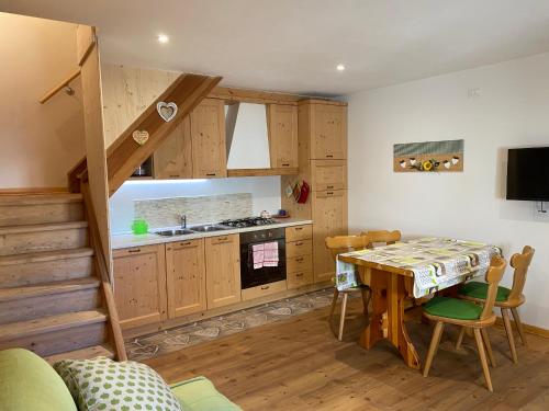 Una cocina y un comedor con una mesa y una escalera. en Al Sole Mountain Chic, en Folgaria