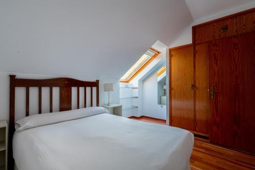 Schlafzimmer mit einem weißen Bett und einem Holzschrank in der Unterkunft Holi-Rent Colina Blanca in Camas