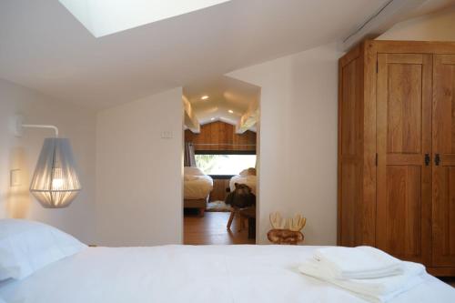 a bedroom with a white bed and a wooden cabinet at L'Etincelle Mountain Lodge in Chamrousse