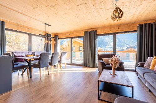 uma sala de estar com um sofá, uma mesa e cadeiras em Bergeralm Chalets by ALPS RESORTS em Steinach am Brenner