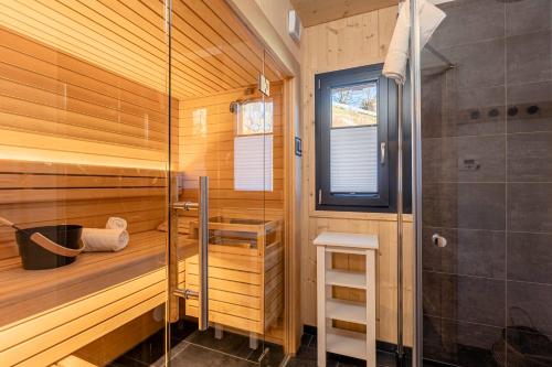 una sauna con ducha y una puerta de cristal en Bergeralm Chalets by ALPS RESORTS, en Steinach am Brenner