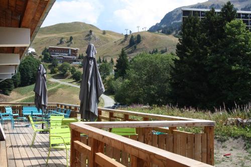 a deck with chairs and umbrellas with mountains in the background at L'Etincelle Mountain Lodge in Chamrousse