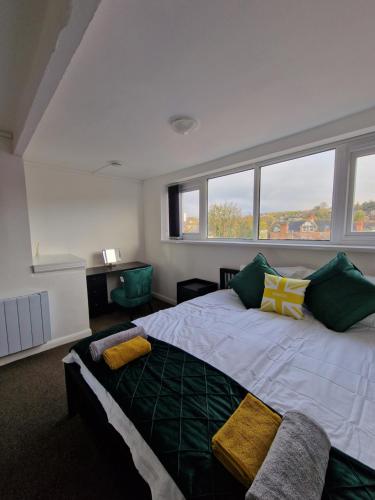 1 dormitorio con 1 cama grande con almohadas verdes y amarillas en Balco Sherwood House - 2 Bedrooms, 5 beds - Sky tv and internet en Nottingham