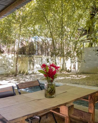 a vase with red flowers sitting on a wooden table at Nativ Lodge and Spa in Mahébourg