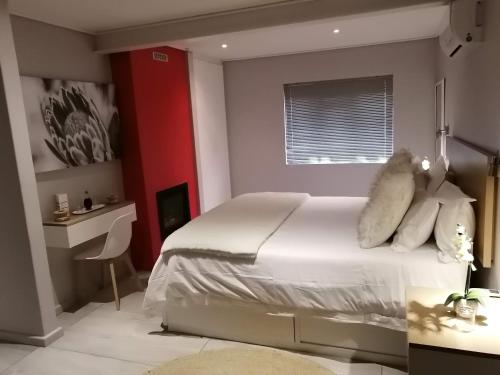 a bedroom with a white bed and a red wall at Lauradale Accommodation in Stellenbosch