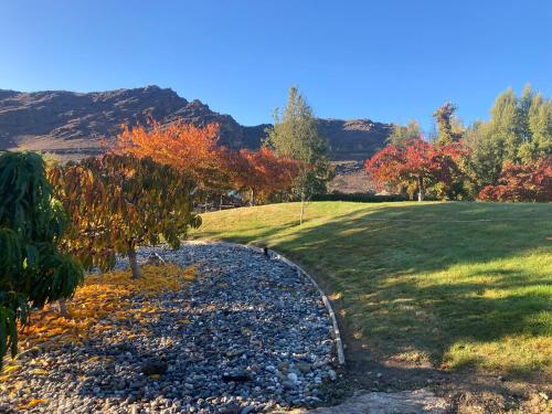 a gravel path in a field with trees and mountains at Lookout Escape Studio, Alexandra in Alexandra