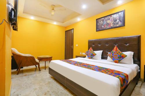 1 dormitorio con 1 cama grande y paredes amarillas en FabExpress Taj Home Stay, en Nueva Delhi