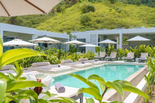 a resort pool with lounge chairs and umbrellas at Amazing Lombok Resort in Selong Belanak