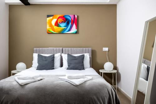 een slaapkamer met een bed met een schilderij aan de muur bij Curb Properties - Super Apartment Moments From Town Centre in Cheltenham