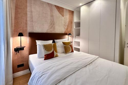 sypialnia z dużym białym łóżkiem z poduszkami w obiekcie OPERA PROMENADE 2 Brand-new! 2 rooms next to the sea w Nicei