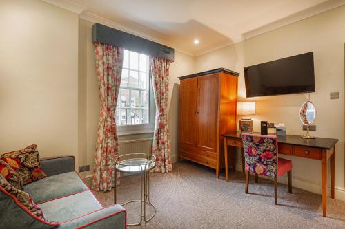 a living room with a couch and a desk and a television at The Wynnstay Hotel, Oswestry, Shropshire - The Coaching Inn Group in Oswestry
