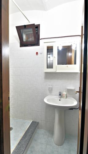 a white bathroom with a sink and a mirror at Villa Very in Marina di Campo