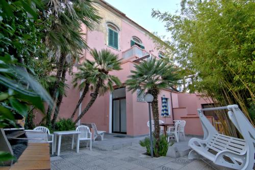 um edifício rosa com cadeiras e palmeiras em frente em Villa Very em Marina di Campo