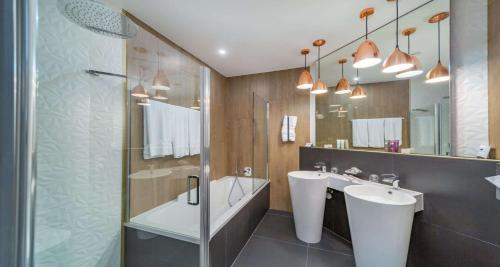 a bathroom with two sinks and a tub and a mirror at MIA SeePark Hotel Murten in Murten