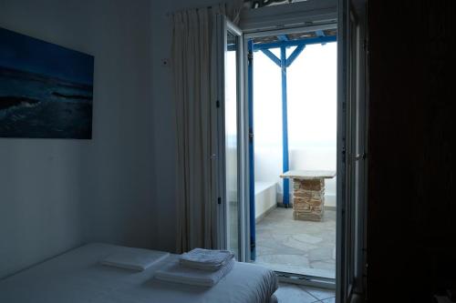 Schlafzimmer mit einem Bett und einer Tür zu einem Balkon in der Unterkunft Beach House in Tinos island in Kardhianí