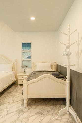 a white bedroom with a bed and a window at ทรายทอง รีสอร์ท in Ban Pru Yai
