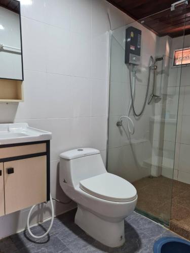 a bathroom with a white toilet and a shower at Lampang Hideaway Guesthouse in Lampang