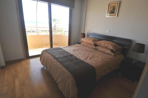 a bedroom with a bed with a view of a balcony at Ithaki Phinikoudes Apartment No. 201 in Larnaka