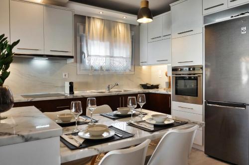 kuchnia z białymi szafkami i stołem z kieliszkami do wina w obiekcie Meteora View Penthouse w Kalambace