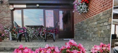 - une terrasse avec une table, des chaises et des fleurs dans l'établissement Maison Raquet, à Jalhay