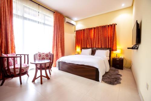 ラゴスにあるRushmore - Paradise Roomのベッド、テーブル、椅子が備わるホテルルームです。