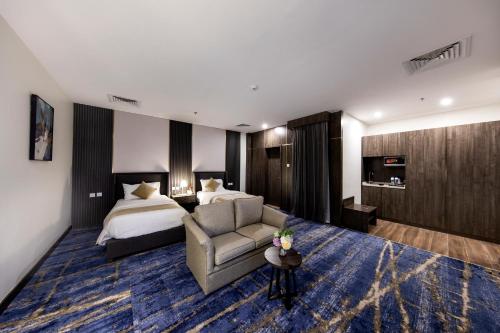 une chambre d'hôtel avec un lit, un canapé et une chaise dans l'établissement Lily Hotel Suite Hofuf, à Al Hofuf