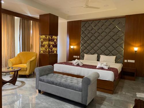 Hotel Hyderabad Grand في شامشاباد: غرفة نوم بسرير واريكة وكرسي