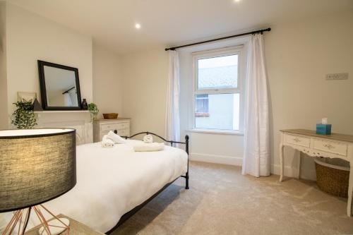 a bedroom with a bed and a window and a desk at Lemon Cottage- Stylish & Modern Home - Town Centre in Newton Abbot