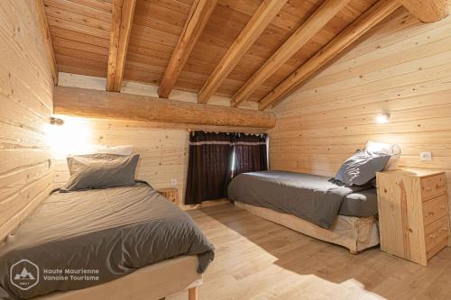 two beds in a log cabin bedroom with wooden walls at Chalet Le Bois Joli in Bonneval-sur-Arc