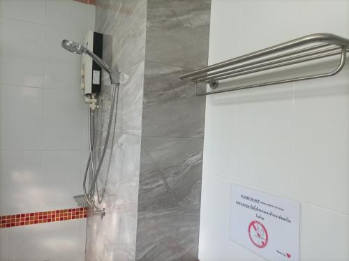 a shower in a bathroom with a sign on the wall at Golden Nest Hotel Suvarnabhumi in Bangkok