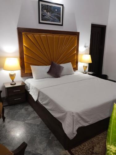 a bedroom with a large bed with a wooden headboard at 1 Kanal Entire House with 4 Bedrooms in Lahore