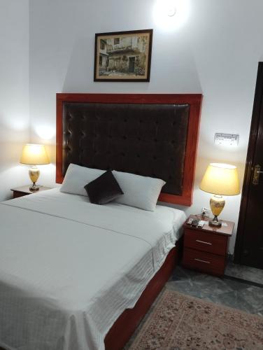 a bedroom with a large bed with two lamps at 1 Kanal Entire House with 4 Bedrooms in Lahore