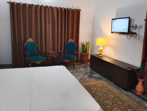 a bedroom with a bed and two chairs and a television at 1 Kanal Entire House with 4 Bedrooms in Lahore