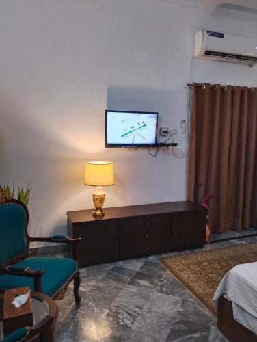 a living room with a tv and a chair and a lamp at 1 Kanal Entire House with 4 Bedrooms in Lahore