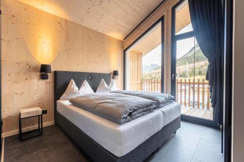 a bedroom with a bed and a large window at Alpenchalets Biberwier Zugspitze by ALPS RESORTS in Biberwier