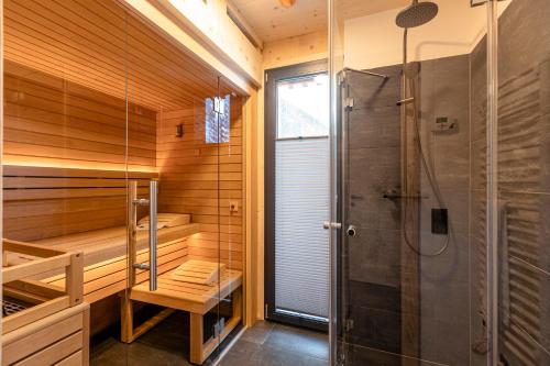 una sauna con ducha y una puerta de cristal en Alpenchalets Biberwier Zugspitze by ALPS RESORTS en Biberwier