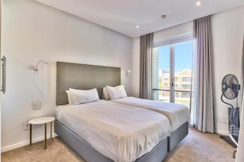a bedroom with a large bed and a large window at Two Bedroom Apartment - fully furnished and design in Va Marina Residential in Cape Town