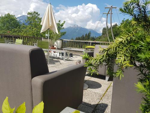 a patio with chairs and an umbrella and mountains at nawu apartments & Restaurant in Hermagor