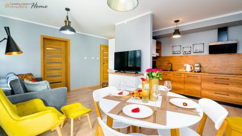 a kitchen and living room with a dining table and yellow chairs at Wonder Home - Apartamenty położone blisko deptaka, licznych restauracji i sklepów in Karpacz