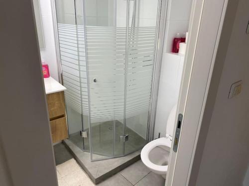 a bathroom with a glass shower and a toilet at דירת נופש - נאות גולף in Caesarea