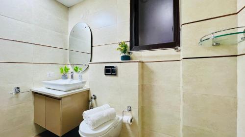 a bathroom with a toilet and a sink and a mirror at Olive Service Apartments - City Centre Noida in Noida