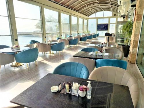 a restaurant with tables and chairs and windows at Mövenpick Hotel & Resort Al Bida'a in Kuwait
